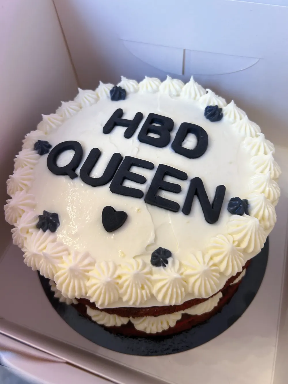 Witte taart met ‘HBD Queen’ in zwarte letters