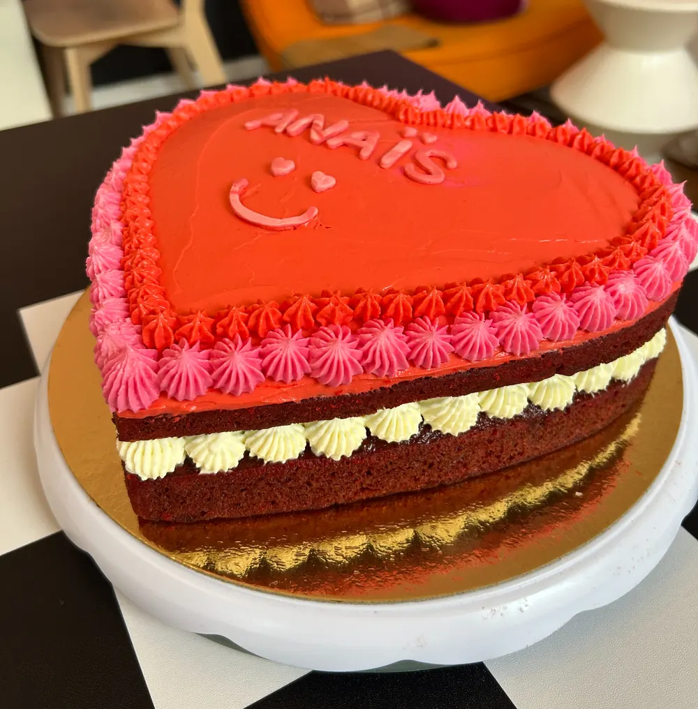 Hartvormige red velvet taart met rode en roze frosting en de naam Anaïs