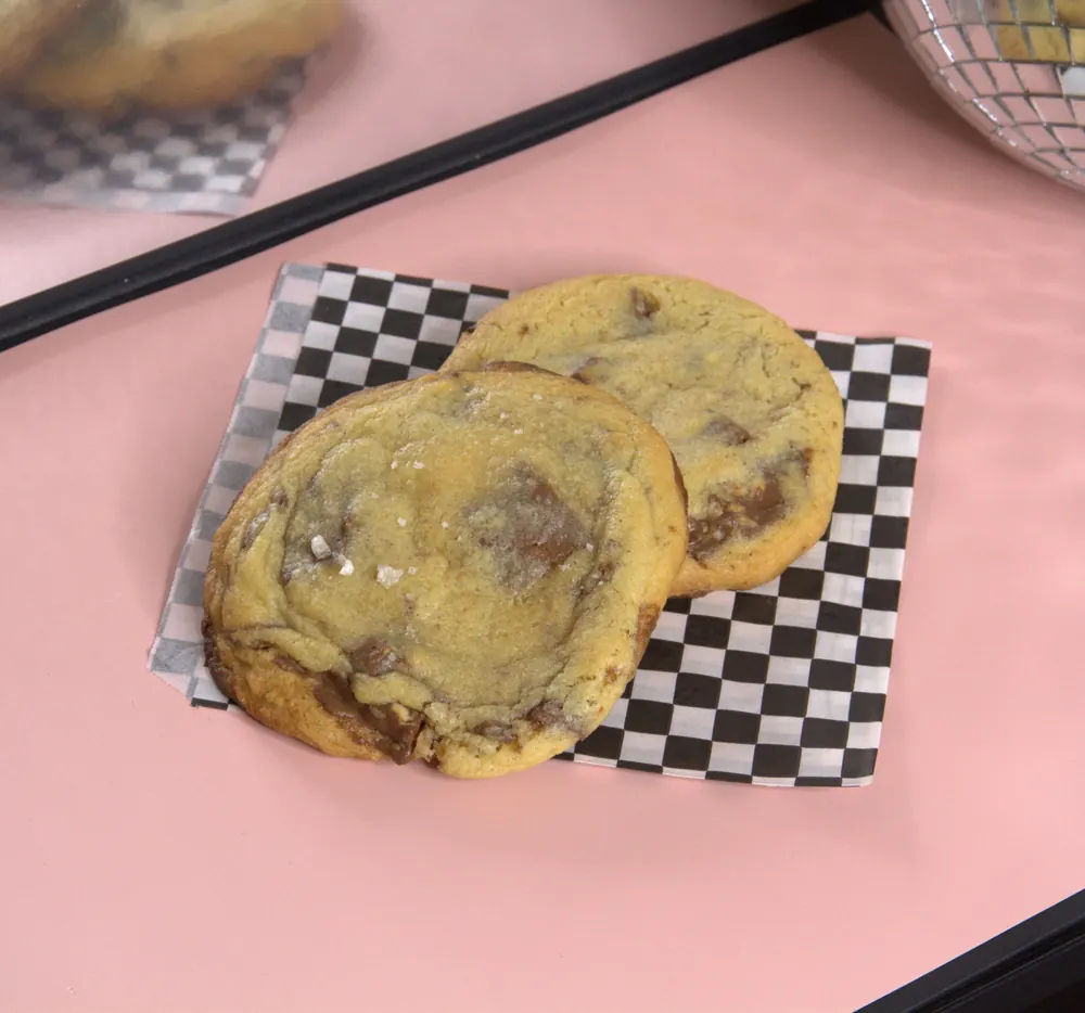 Twee NYC-style choco chip cookies op een geblokt papiertje
