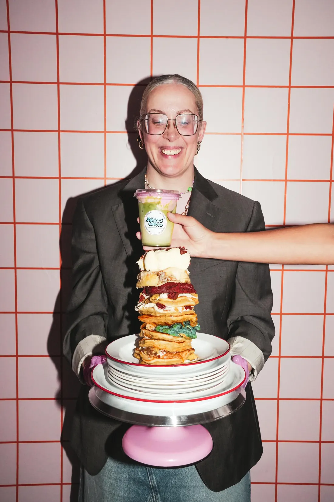 Jessie Van Osselt, oprichter van Naked Cakes, met een toren van pancakes, cookies en een pink matcha