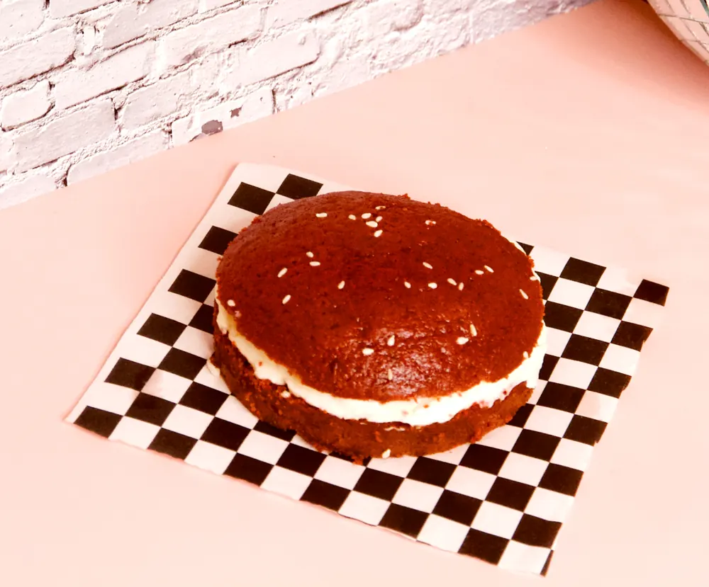 Red velvet ‘burger’ met cream cheese frosting op een geblokte onderlegger